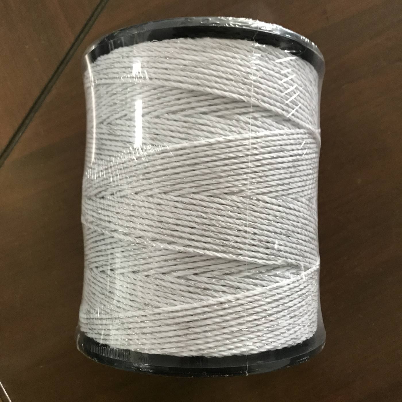 White solid-braided rope on a black spool