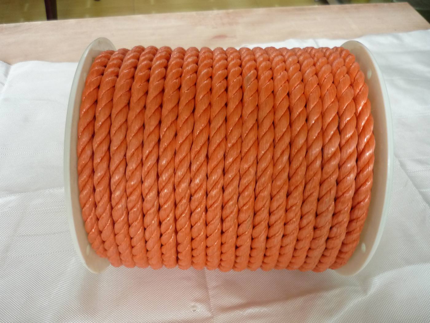 Orange 3-strand twisted polypropylene rope on a small plastic spool