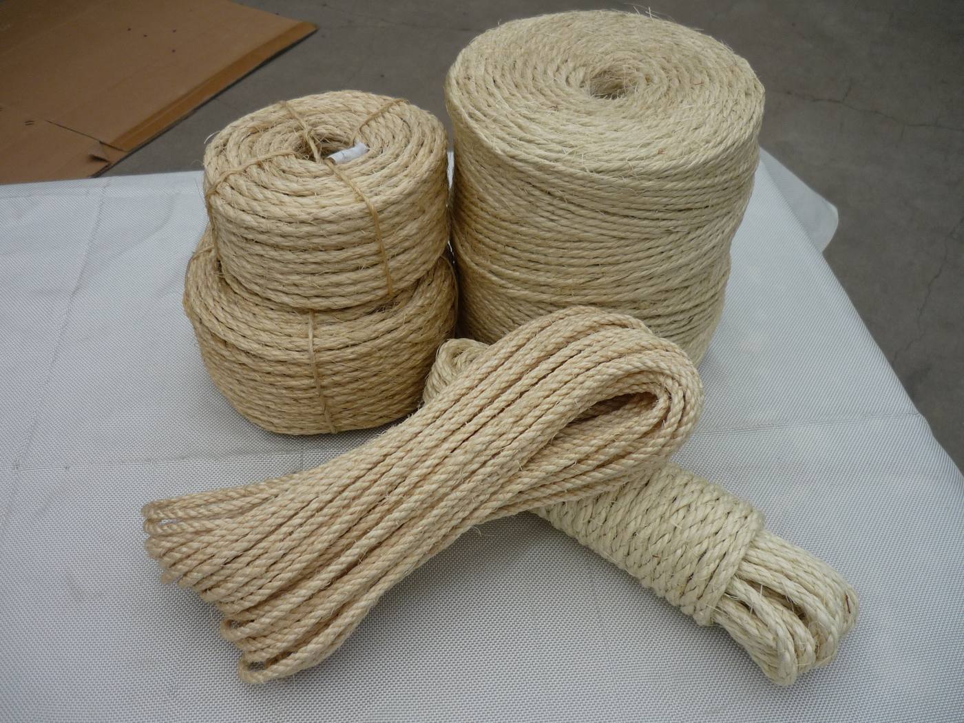 Natural jute 3-strand twisted rope coils and hanks, on a white surface